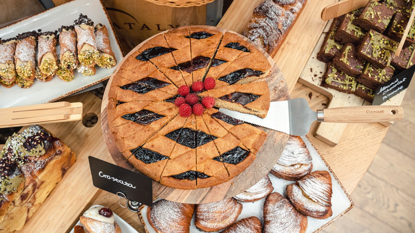 Assortimento di dolci tra cui crostata ai lamponi e cannoli.