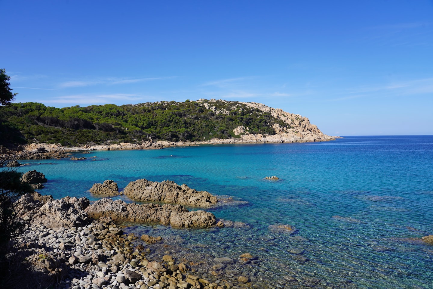 Costa rocciosa con acqua turchese e scogliere verdi e lussureggianti.