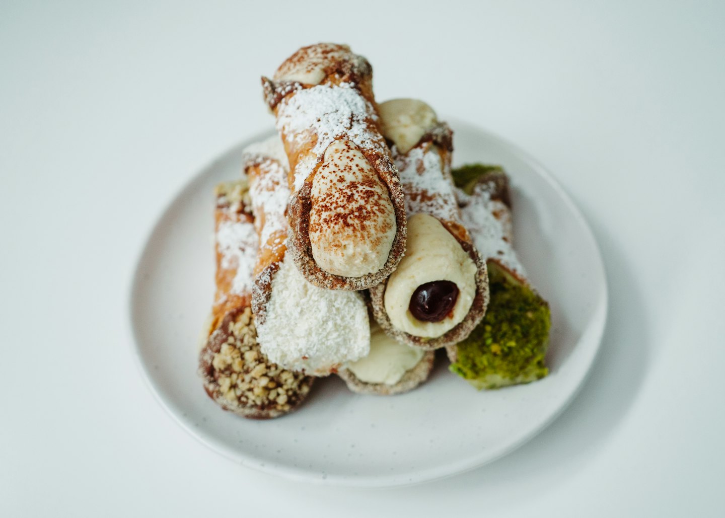 Assortimento di cannoli guarniti con noci e zucchero su un piatto.