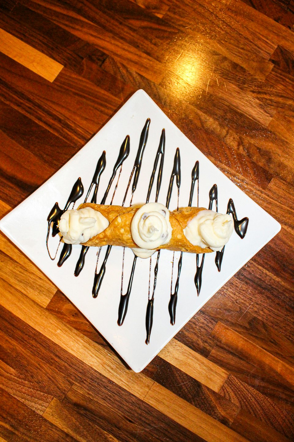 Cannoli con panna e gocce di cioccolato su un piatto bianco.