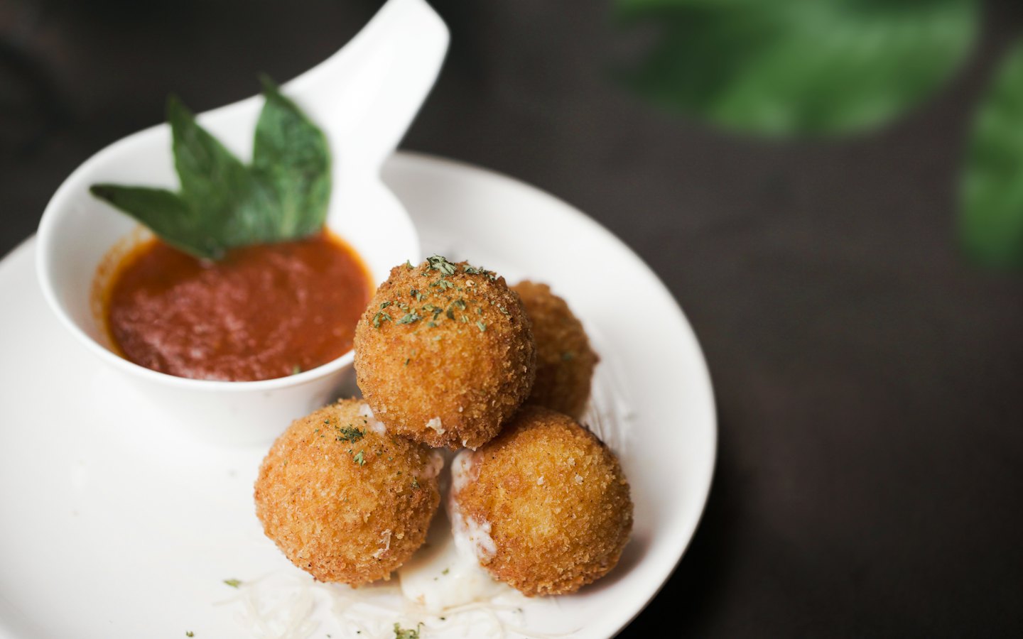 Arancini fritti serviti con salsa rossa su un piatto.